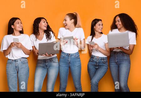 Multiethnic Women Using Gadgets, Computers And Smartphones Over Yellow Background Stock Photo