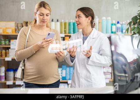 Pregnant woman comparing generic and brand medication with pharmacist Stock Photo