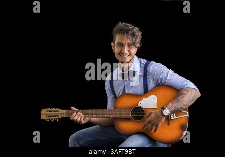 Handsome young man in bow-tie with guitar looking at camera.Studio shot Stock Photo
