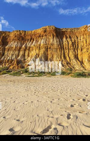 Incredible rock formations on the Atlantic. Red cliffs of sand and pebbles with amazing formations on the sandy beach. A warm sunset bathes the landsc Stock Photo