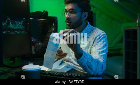 Arabian Indian man male guy programmer examining writing binary code coder freelancer engineer worker IT specialist monitor analyzing computer Stock Photo