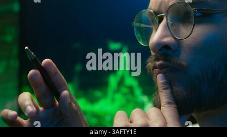 Arabian Indian man analyst programmer holding pen pointing coder hacker work planning male pondering thinking imagination businessman calculating Stock Photo