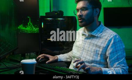Tired sleepy Indian Arabian man worker typing keyboard computer late night home office male guy yawning businessman business programmer coder trader Stock Photo