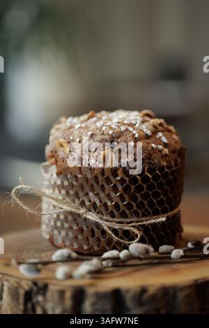 Artisan chocolate Easter cake with hazelnuts and sugar topping, wrapped in eco paper on rustic wood slab. Stock Photo