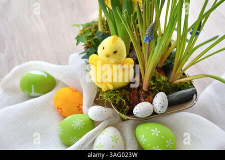 Yellow chick with Easter eggs and spring primroses in a pot on linen cloth. Happy Easter concept Stock Photo