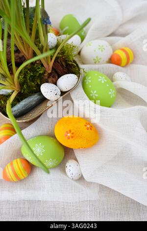 Colorful easter eggs on linen cloth and spring primroses in a pot. Easter still life Stock Photo