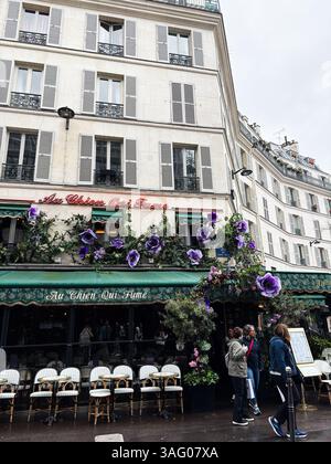 Paris, France - March 28, 2025: A charming street view of a Paris cafe featuring floral decorations and city atmosphere Stock Photo
