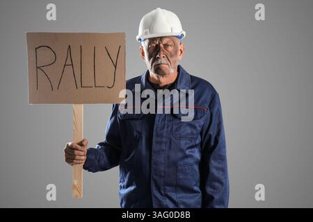 Protesting miner man with placard on grey background Stock Photo