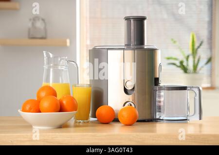 Modern juicer with oranges on table in kitchen Stock Photo