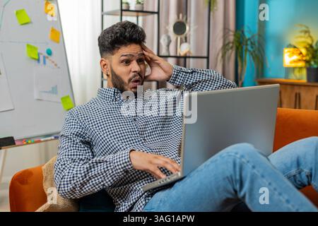Frustrated Indian Arabian man having software problems with laptop. Angry guy nervous seeing error or mistake notification at computer screen, mad employee experience virus attack or app malfunction. Stock Photo
