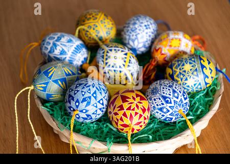 A basket filled with beautifully decorated Easter eggs features traditional Ukrainian pysanky, each displaying intricate folk patterns in vibrant colors. Stock Photo