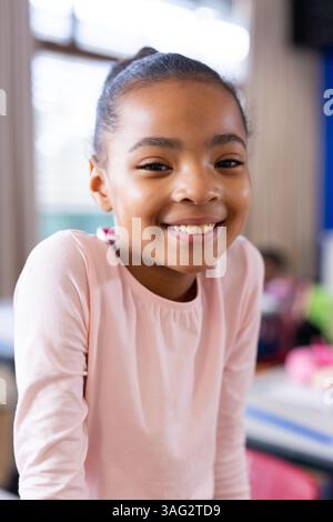 Smiling girl in school classroom, looking at camera, feeling happy Stock Photo