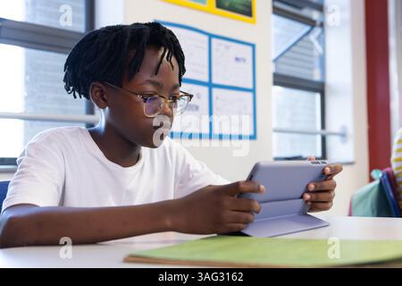 In school, african american boy using tablet at desk, focusing on digital learning Stock Photo