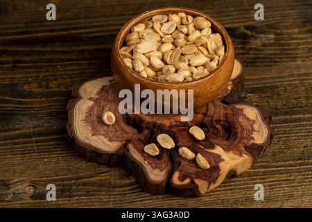 peeled peanut kernels in a wooden bowl, fried yellow peanuts with a little salt on the table Stock Photo
