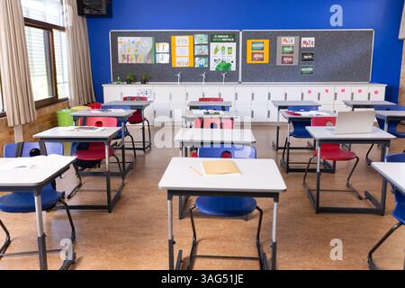 Empty classroom with desks and chairs neatly arranged, ready for students, copy space Stock Photo