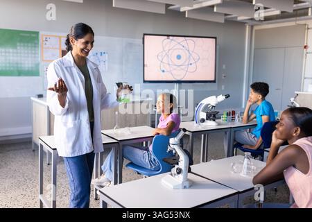 In school, Indian female teacher conducting science experiment with students in classroom Stock Photo