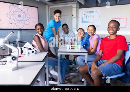 In school science lab, group of students smiling and sitting around table Stock Photo