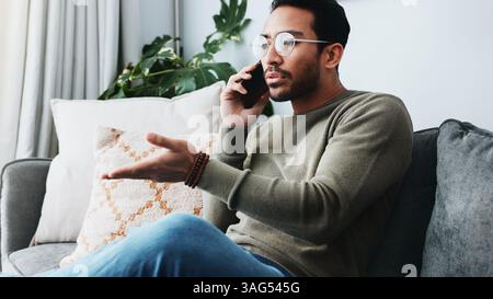 Phone call, frustrated and man on sofa in home for client feedback with freelance job. Cellphone, remote work and male person on mobile discussion Stock Photo