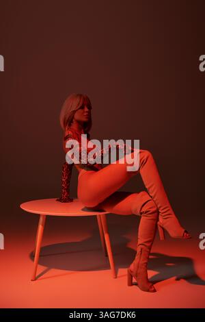 Young woman with intricate tattoos poses confidently on a round table in striking red hues Stock Photo