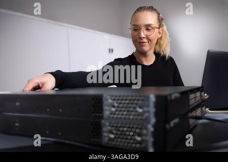 Female IT consultant in datacenter configuring switches in server and network room Stock Photo