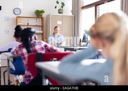 Female teacher engaging with diverse students in classroom, children ...
