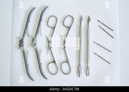 A set of clean and sterilized stainless steel manicure tools arranged on a white paper towel Stock Photo