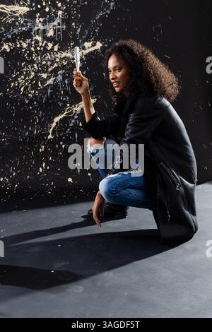 Artist in grunge studio holding paintbrush, creating abstract wall art. painting, creativity, contemporary, expression, artistic Stock Photo