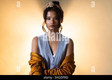 Young woman in stylish outfit posing confidently in grunge studio setting. Fashion, style, trend, urban, attitude, edgy Stock Photo
