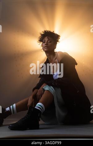 African American woman sitting confidently in studio with dramatic lighting. Portrait, confidence, beauty, elegance, powerful, artistic Stock Photo