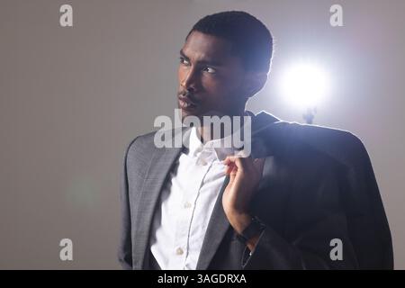 Confident man in stylish suit posing under bright studio spotlight. Fashion, formalwear, elegance, businessman, confidence, style Stock Photo