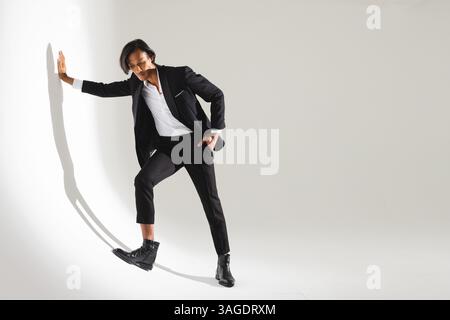 Confident man in stylish black suit posing against white studio wall. Fashion, luxury, elegance, formal, style, sophisticated Stock Photo