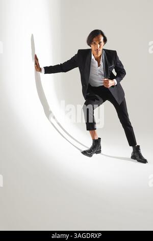 Confident man in stylish suit posing dynamically in modern studio. Business, professional, fashion, elegance, confidence, corporate Stock Photo