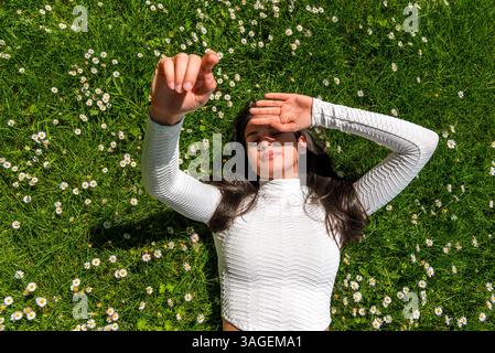 Above view with a young woman lying on the green grass in bright sunlight Stock Photo