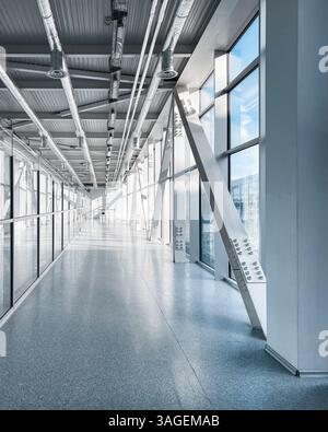 Empty long corridor in the airport terminal. Diminishing perspective view of long glass corridor leading to a jet bridge. Stock Photo