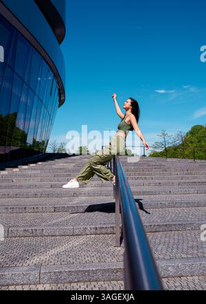 Young woman with arms raised smiling and having fun in the bright sunlight Stock Photo