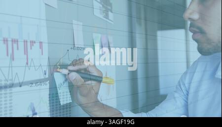 Image of interface with graphs and data with man in office making notes on wall Stock Photo
