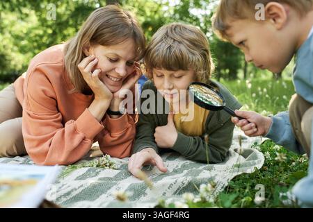 Mother with Two Boys Using Magnifying Glass Looking at Bugs  Stock Photo