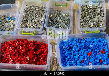 Colorful plastic and metal eyelets cable connectors piles in plastic boxes outside on market Stock Photo