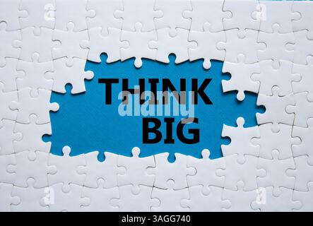 Think big symbol. White puzzle with words Think big. Beautiful blue background. Business and Think big concept. Copy space. Stock Photo
