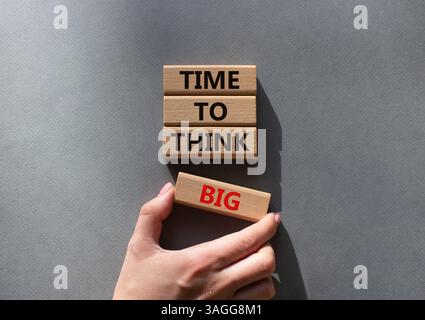 Time to think big symbol. Wooden blocks with words Time to think big. Beautiful grey background. Businessman hand. Business and Time to think big conc Stock Photo