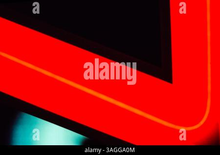 Angled corner of a red neon sign bulb with an orange centerline on black background Stock Photo