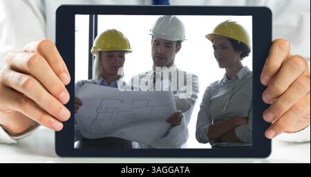 Hands holding digital tablet showing architect discussing plans over blueprint Stock Photo