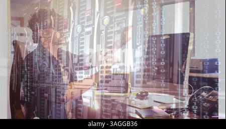 Binary code and data servers over person working at computer in office Stock Photo