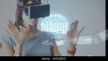 Using virtual reality headset, woman interacting with robotic hand and holographic brain Stock Photo