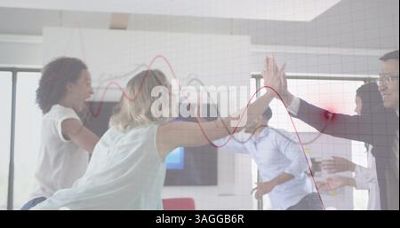 Financial data processing against group of office colleagues high fiving each other at office Stock Photo