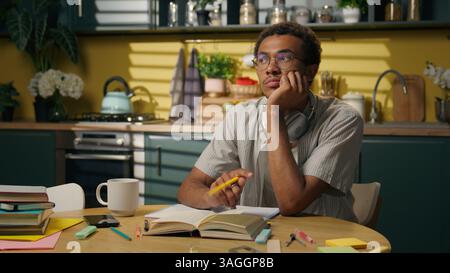 Thinking pensive deep thoughts African American guy sad thoughtful business man male freelancer student think problem studying at kitchen difficult Stock Photo