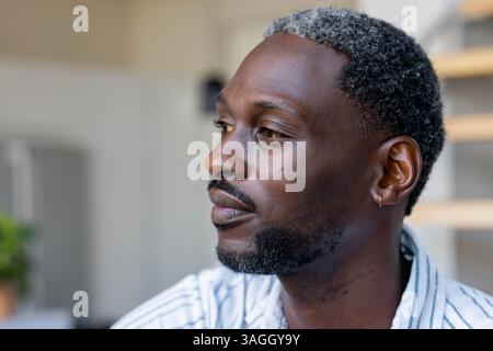 Thoughtful African American African American man relaxing at home, looking out window. Relaxation, contemplation, solitude, indoors, tranquility, refl Stock Photo