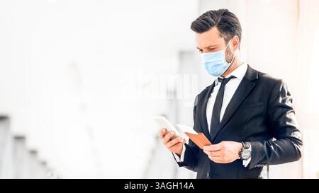 Entrepreneur in face mask using phone while waiting for flight Stock Photo
