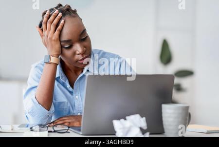 Creativity Crisis. Stressed black female freelancer looking at laptop screen with despair Stock Photo