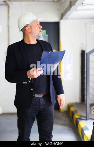 Building inspector with clipboard checking interior construction site for compliance. Stock Photo